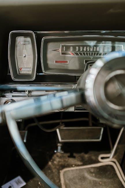 Close-up of a vintage car dashboard featuring a classic speedometer and steering wheel.