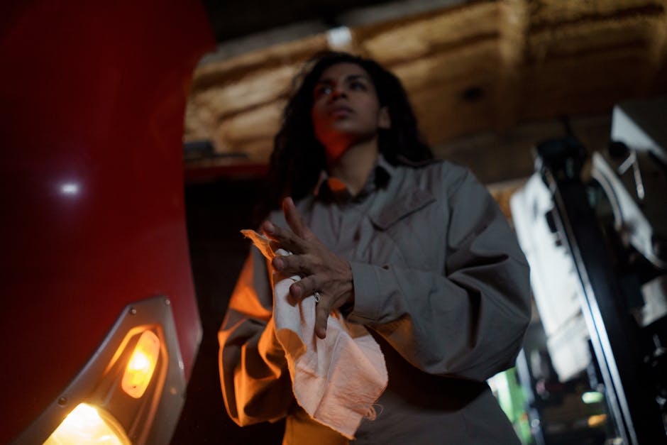 A focused Hispanic female mechanic wipes her hands with a towel in an auto shop.